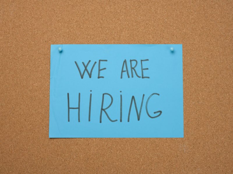 blue sheet of paper with an inscription we are hiring on a brown cork board. Recruitment concept, vacancy